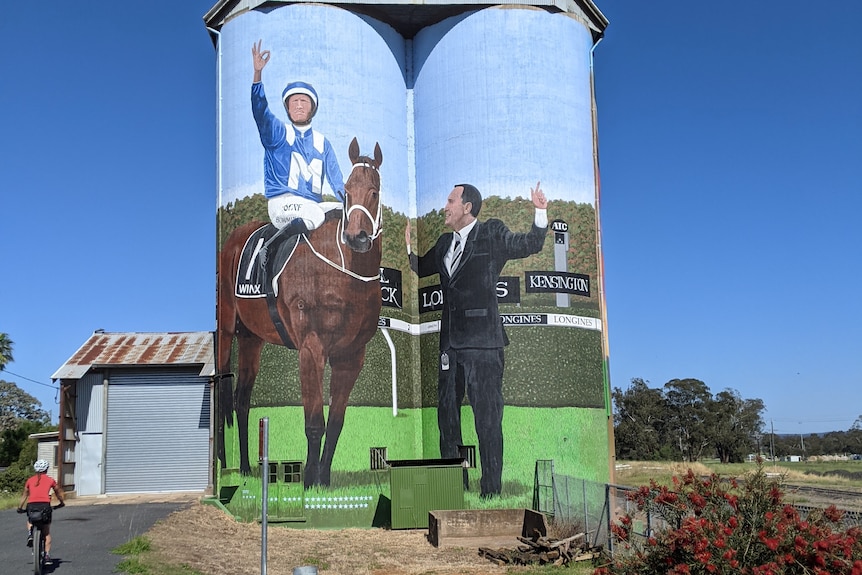 Two silos are painted with a picture of Winx and it's trainer.