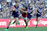 Fremantle Dockers captain Nat Fyfe brushes off a tackle from Essendon's Mark Baguley with two Dockers teammates behind him.