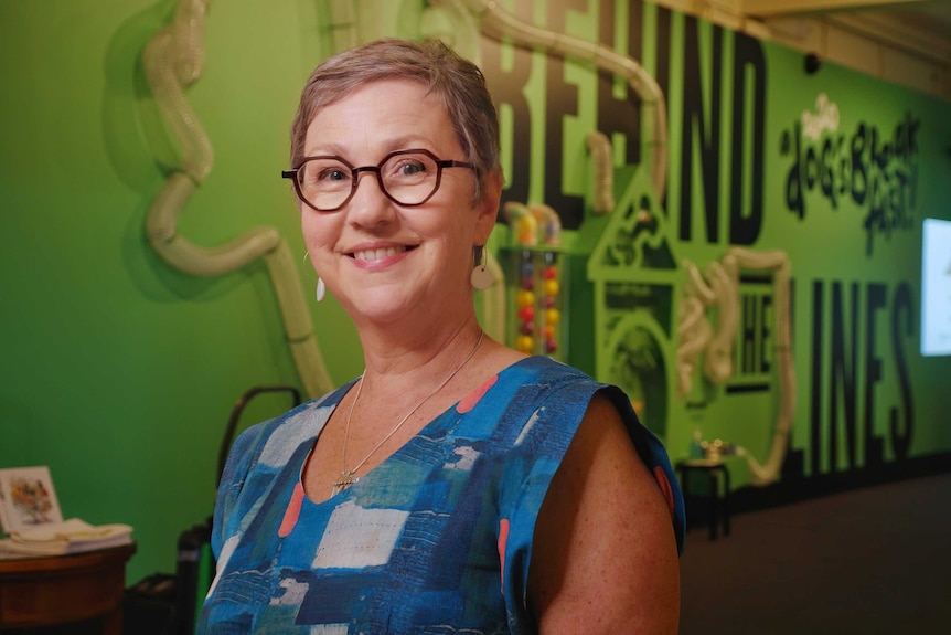 A woman with glasses smiles at the camera.