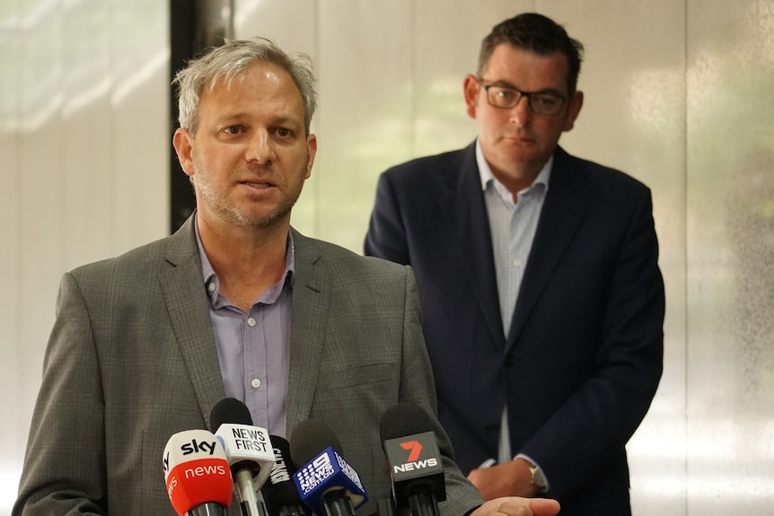 Victorian Chief Health Officer Brett Sutton addresses media wearing a grey jacket and a button-up shirt.