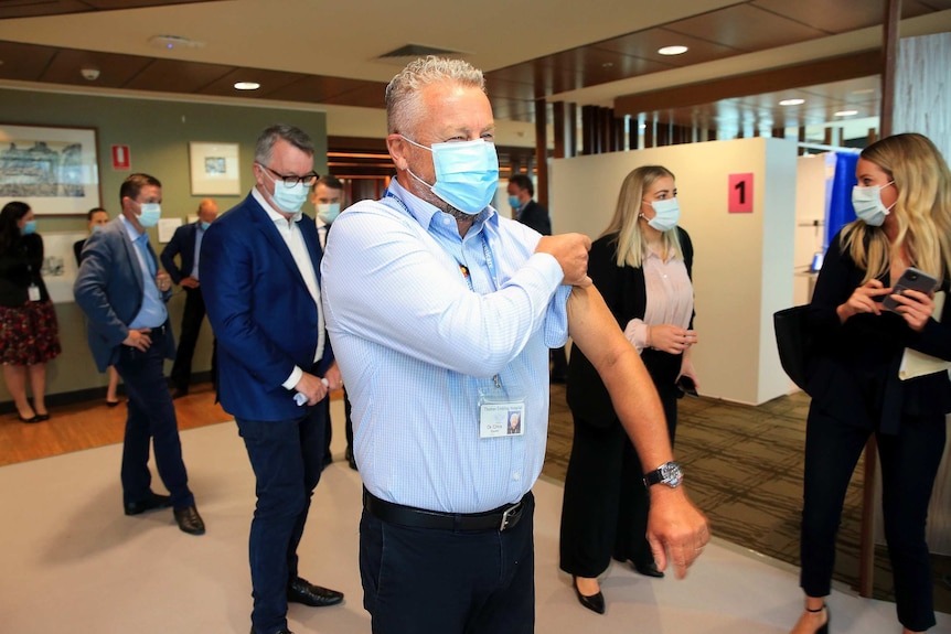 Doctor Chris Quinn wears a mask and adjusts his sleeve.