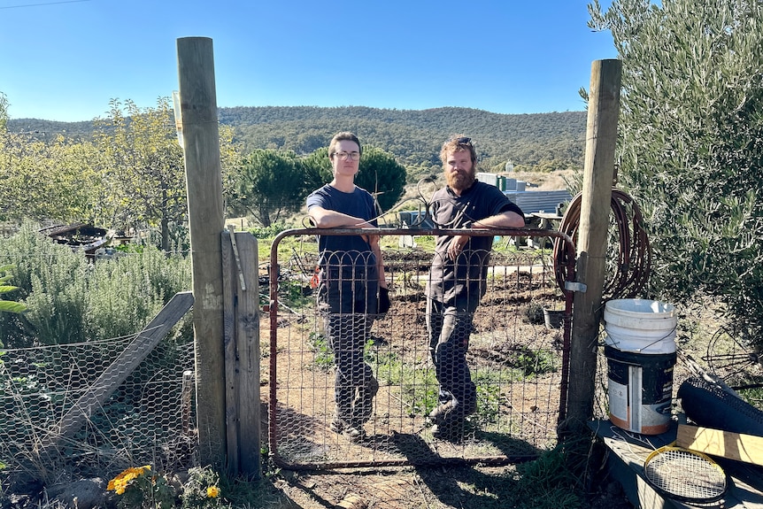Two people standing at their farm gate.