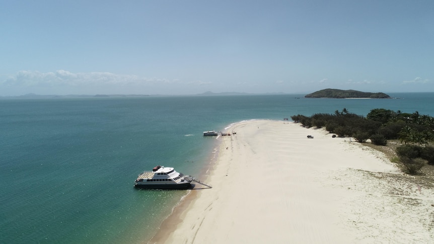 Drone shot of a boat parked up on a tropical island.