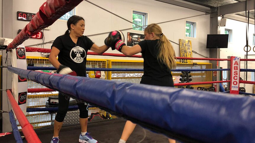 Boxing coach Shara Romer training a woman at her gym.
