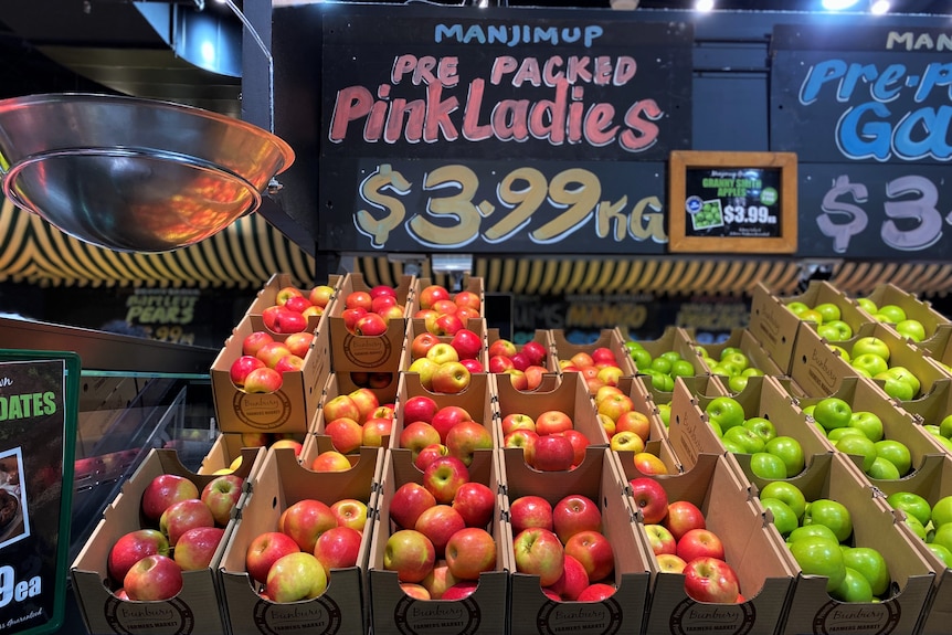 Apples in boxes at supermarket stall.