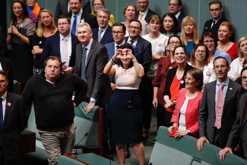 Emma Husar makes a heart sign surrounded by MPs