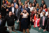 Emma Husar makes a heart sign surrounded by MPs