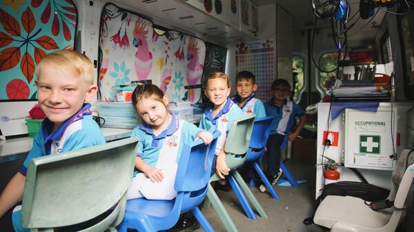 Children sit in their mobile classroom