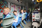 Children sit in their mobile classroom
