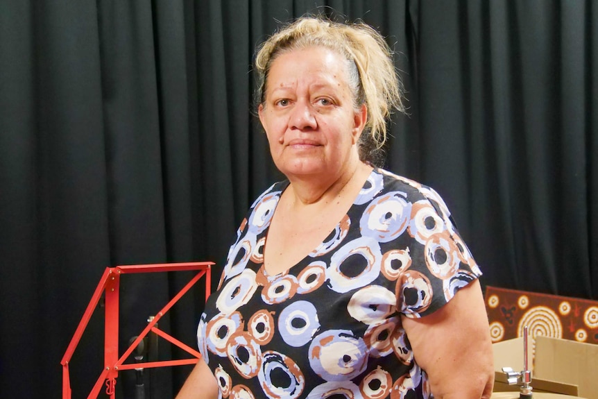 A woman standing in front of a black curtain in a music room