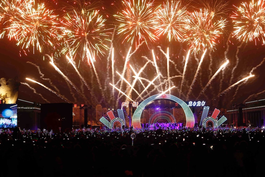 A crowd is seen in front as colourful fireworks explode in the sky.