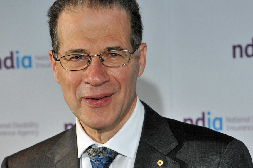 A portrait shot of a man wearing glasses and a suit.