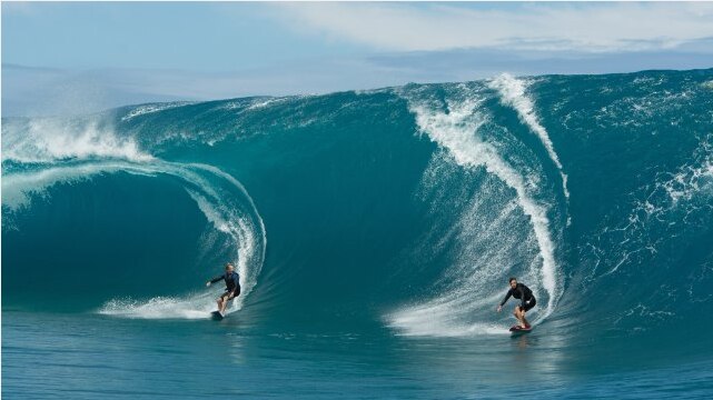 Two men surfing large waves.