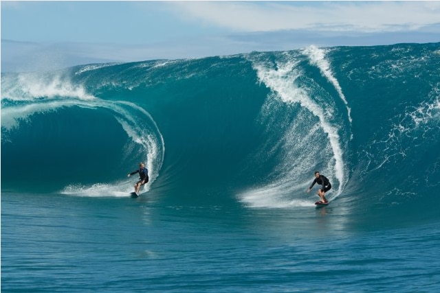 Two men surfing large waves.
