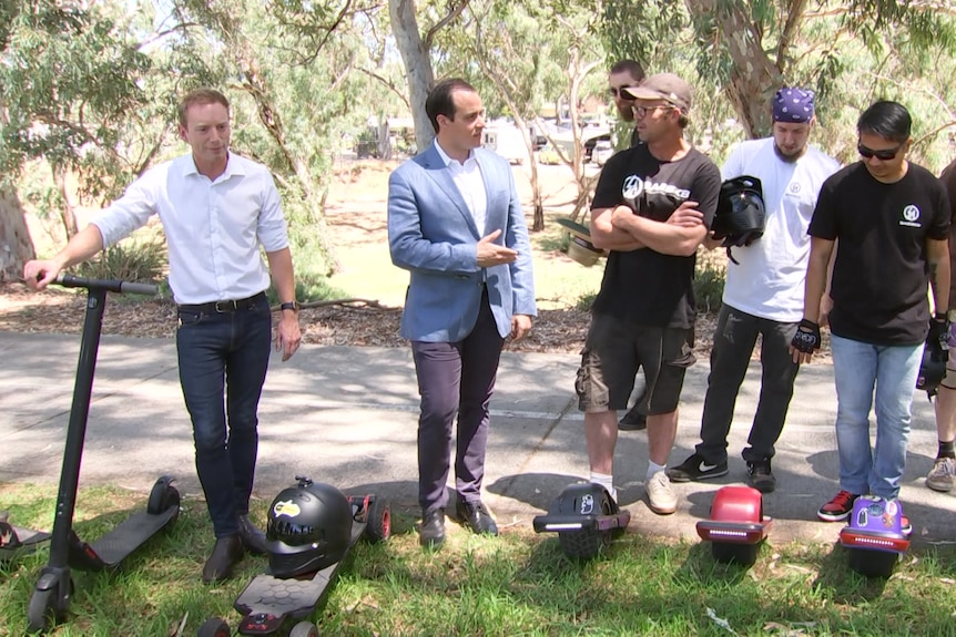 A group of men with scooters and helmets