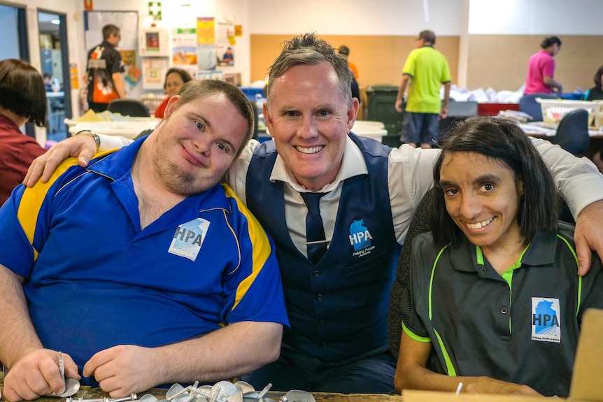 Helping People Achieve chief executive Tony Burns with his arms around Adam Rollo and Jocelyn Ryder