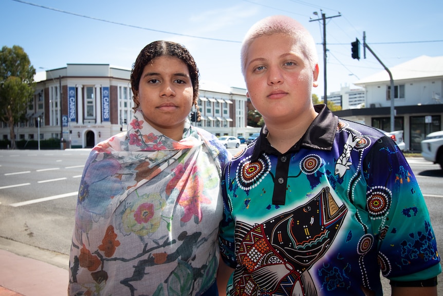 Two Indigenous female students stand in front of high school.