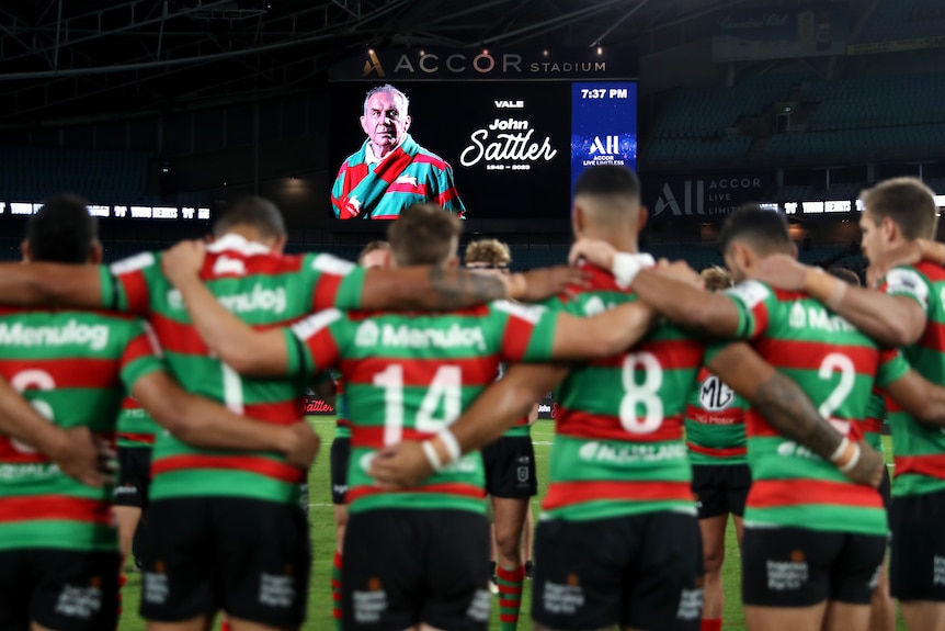 South Sydney NRL players in a circle as they pay respect to John Sattler.