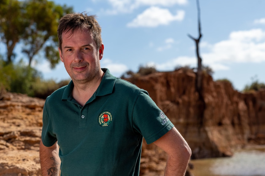 A man stands in a river bed.