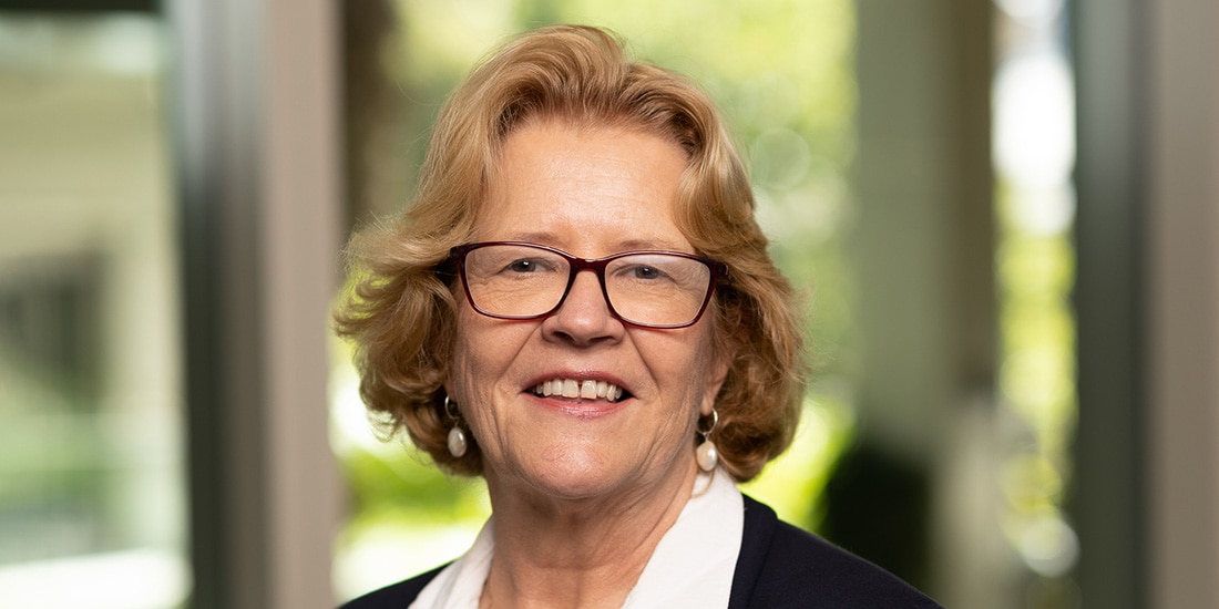 A blonde woman with glasses smiles at the camera