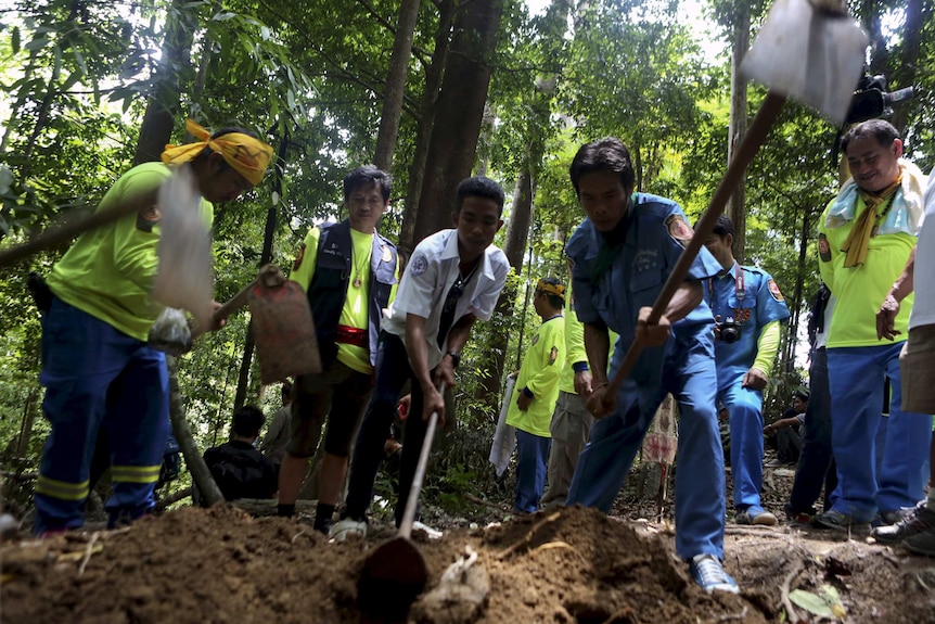 Rescue workers inspect a mass grave at an abandoned camp in a jungle in Thailand's south