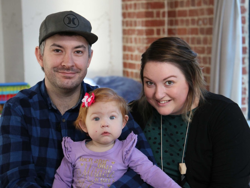 A man and a woman with a young child sitting between them.