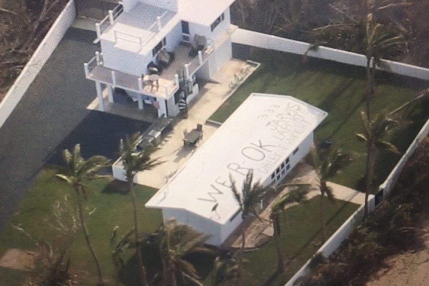 A home with "We R OK" painted on the roof.