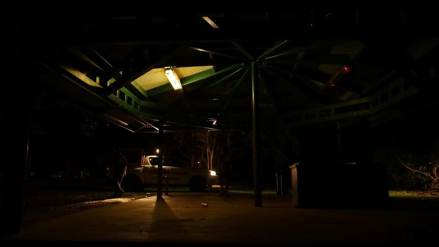 A vehicle with its headlights on pulling up to a rotunda at night.