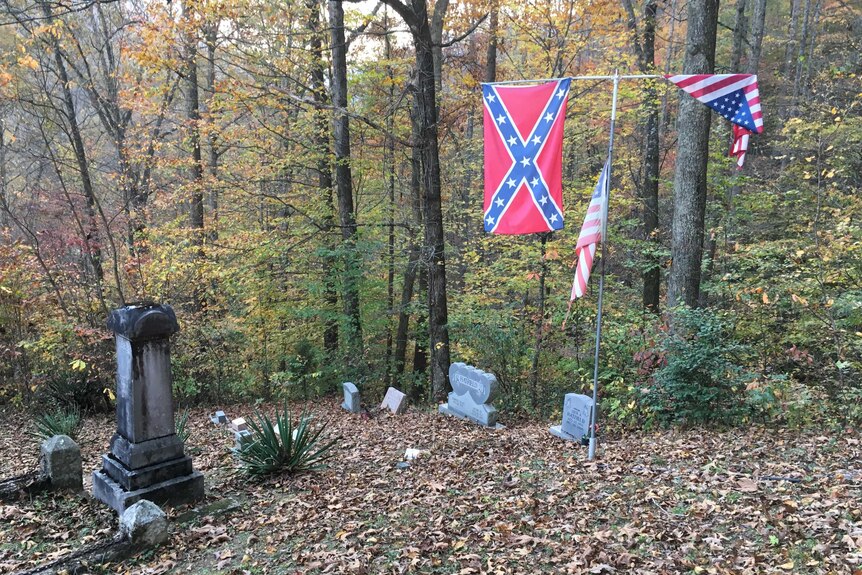 A Confederate flag hangs on a flagpole in a graveyard in Logan County.