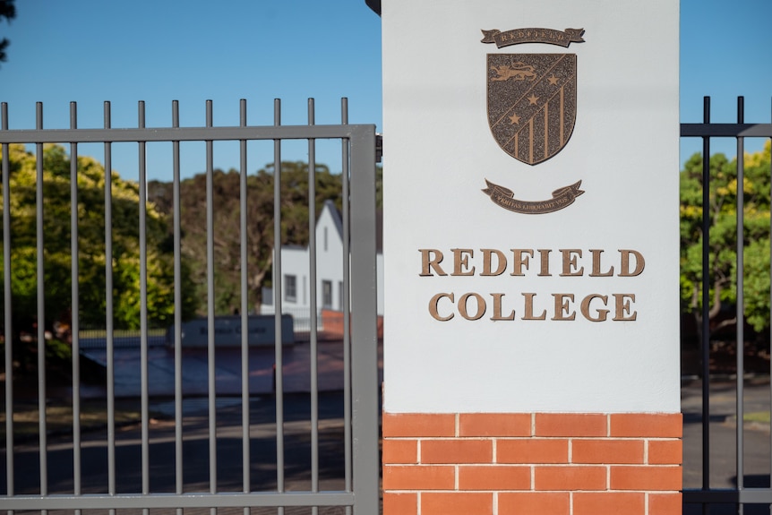 A sign with the words Redfield College next to a metal gate 
