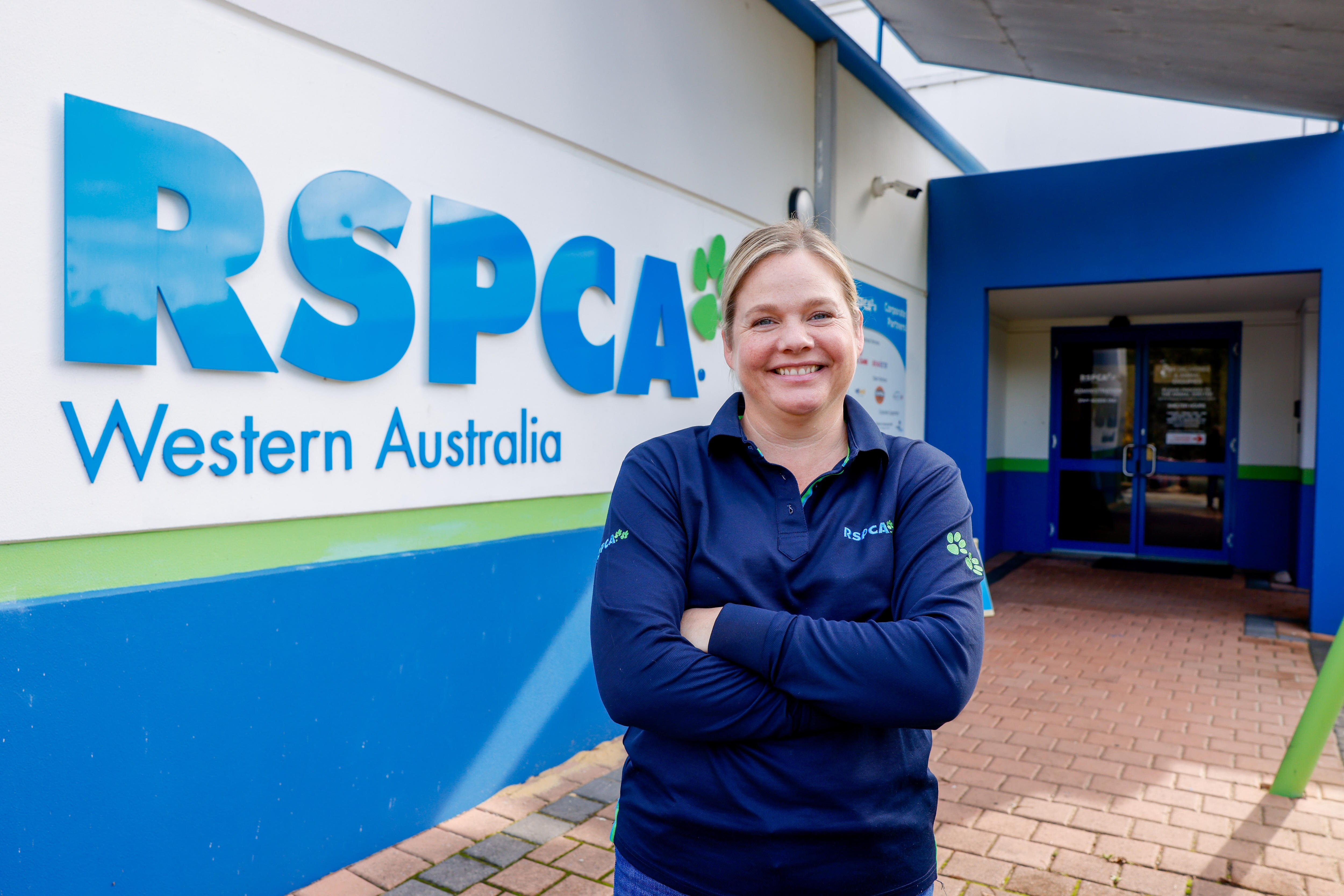 Woman in blue jumper with arms folded in front of RSPCA sign.