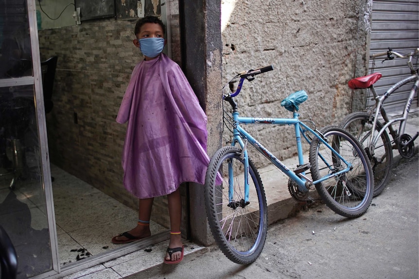 A boy wearing a protective face mask as a precaution against coronavirus while waiting to have his hair cut.
