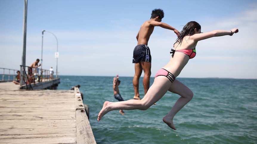 Eddie and Ellie from Epping jump off the Altona pier, during the Melbourne heatwave on December 18, 2015.