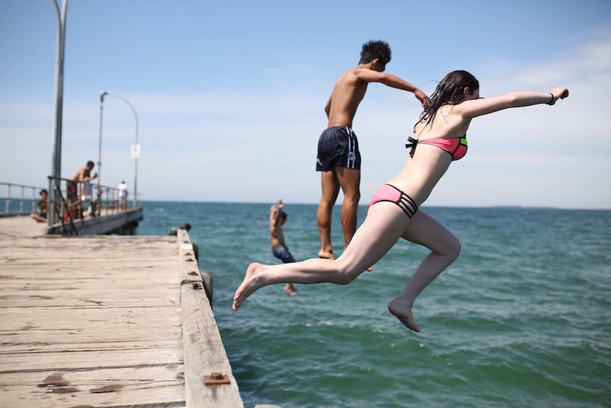 Eddie and Ellie from Epping jump off the Altona pier, during the Melbourne heatwave on December 18, 2015.