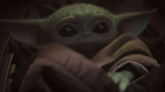 A close up of Mandalorian character Baby Yoda, wearing a brown robe.