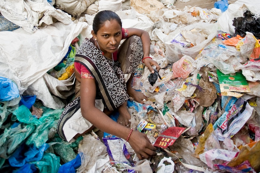 A woman in traditional Indian dress wading in rubbish. 