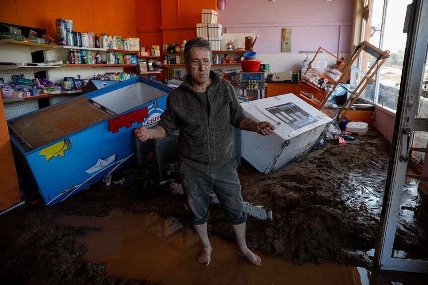 Dimitris Siskos, 77, stands inside his destroyed shop after storms in Kineta village,