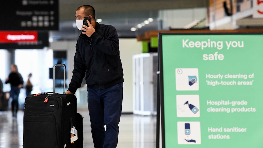 A man at an airport with a suitcase.