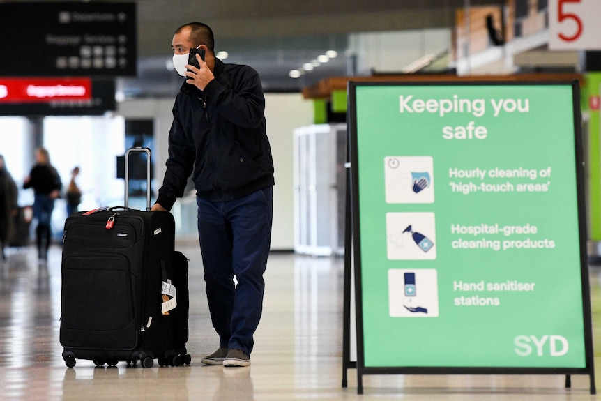 A man at an airport with a suitcase.