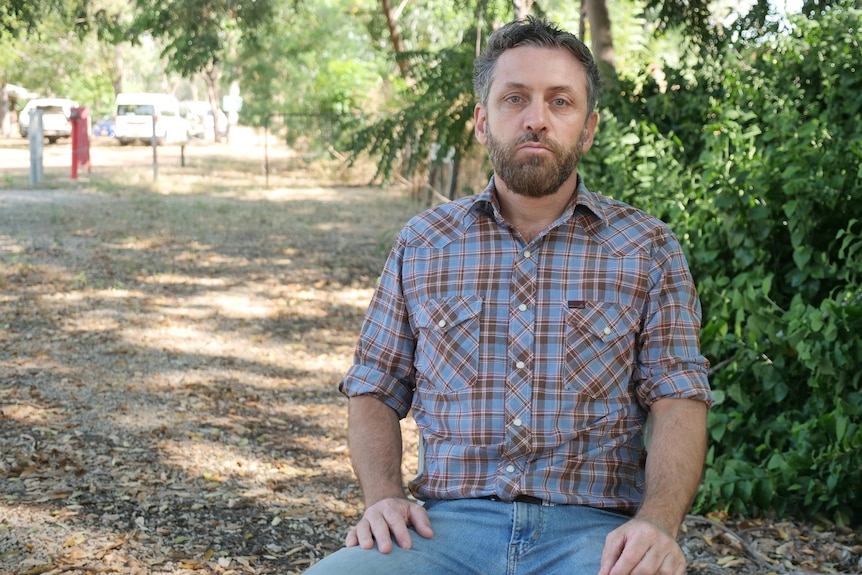 a man sitting down wearing a collared shirt