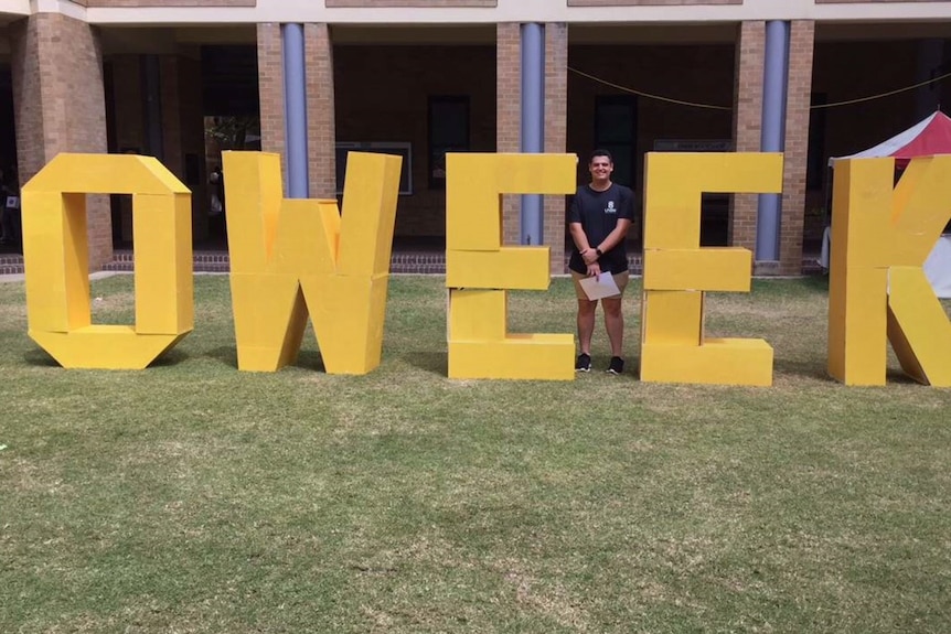 Christopher Loukaitis standing next to the OWEEK sign at University of NSW.