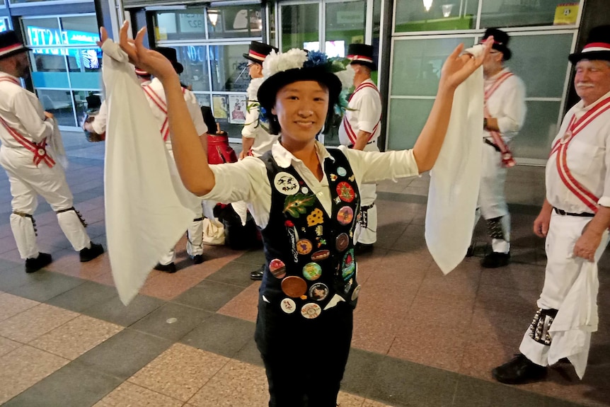 A woman holds white handkerchiefs in the air while men behind her do the same