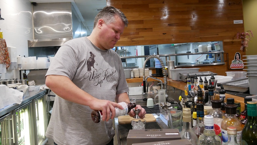 Man in grey shirt pours drinks 