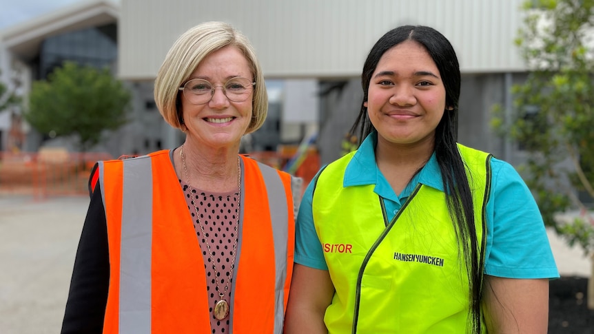 Two women wearing hi vis vests smiling