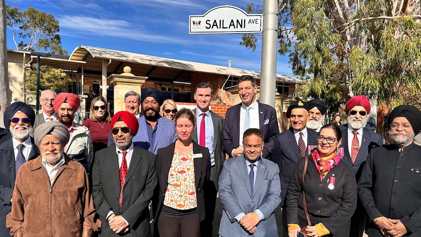 A group photo of people standing under the Saliani Avenue street sign