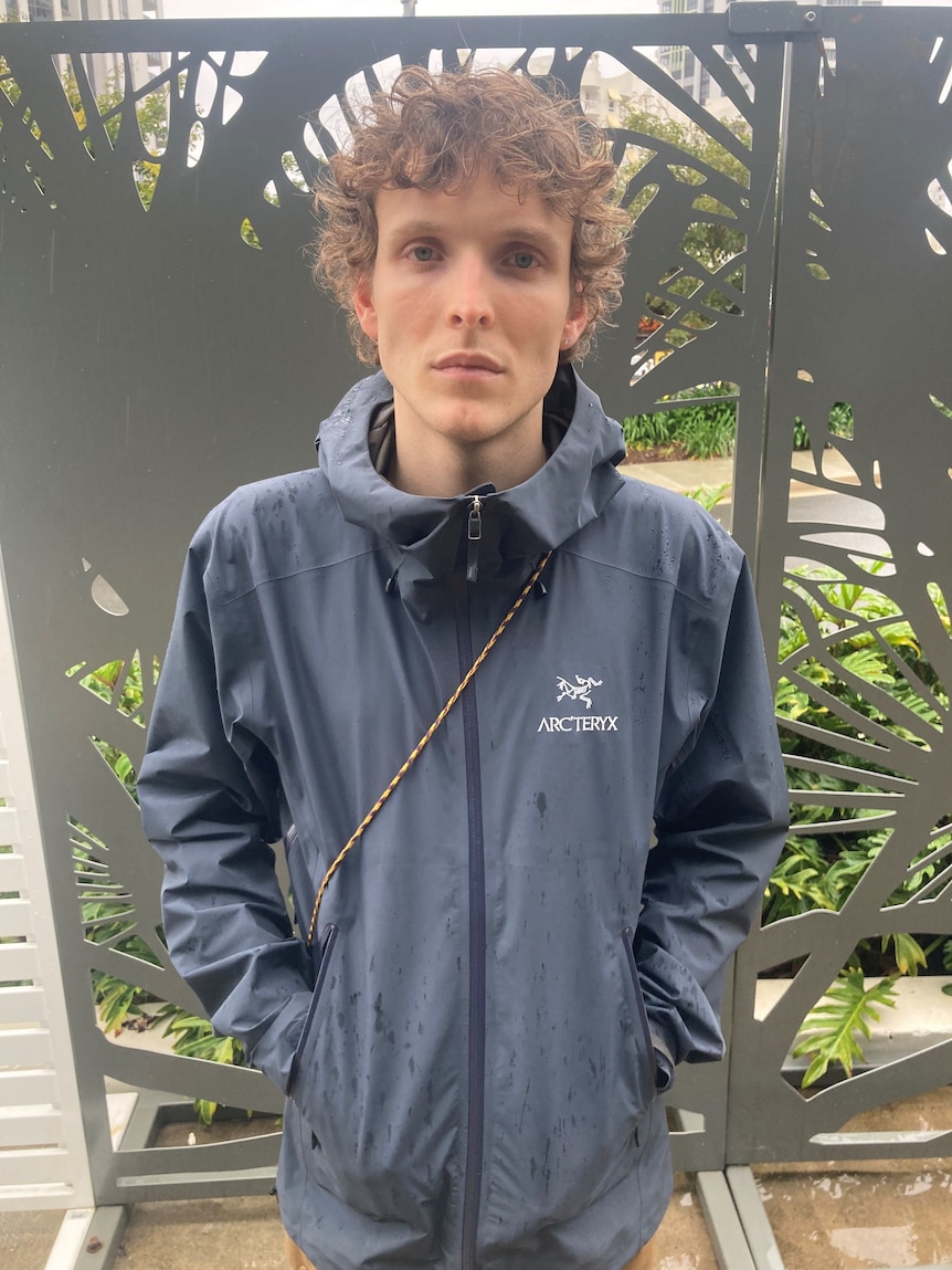 A man with curly hair looks straight into the camera