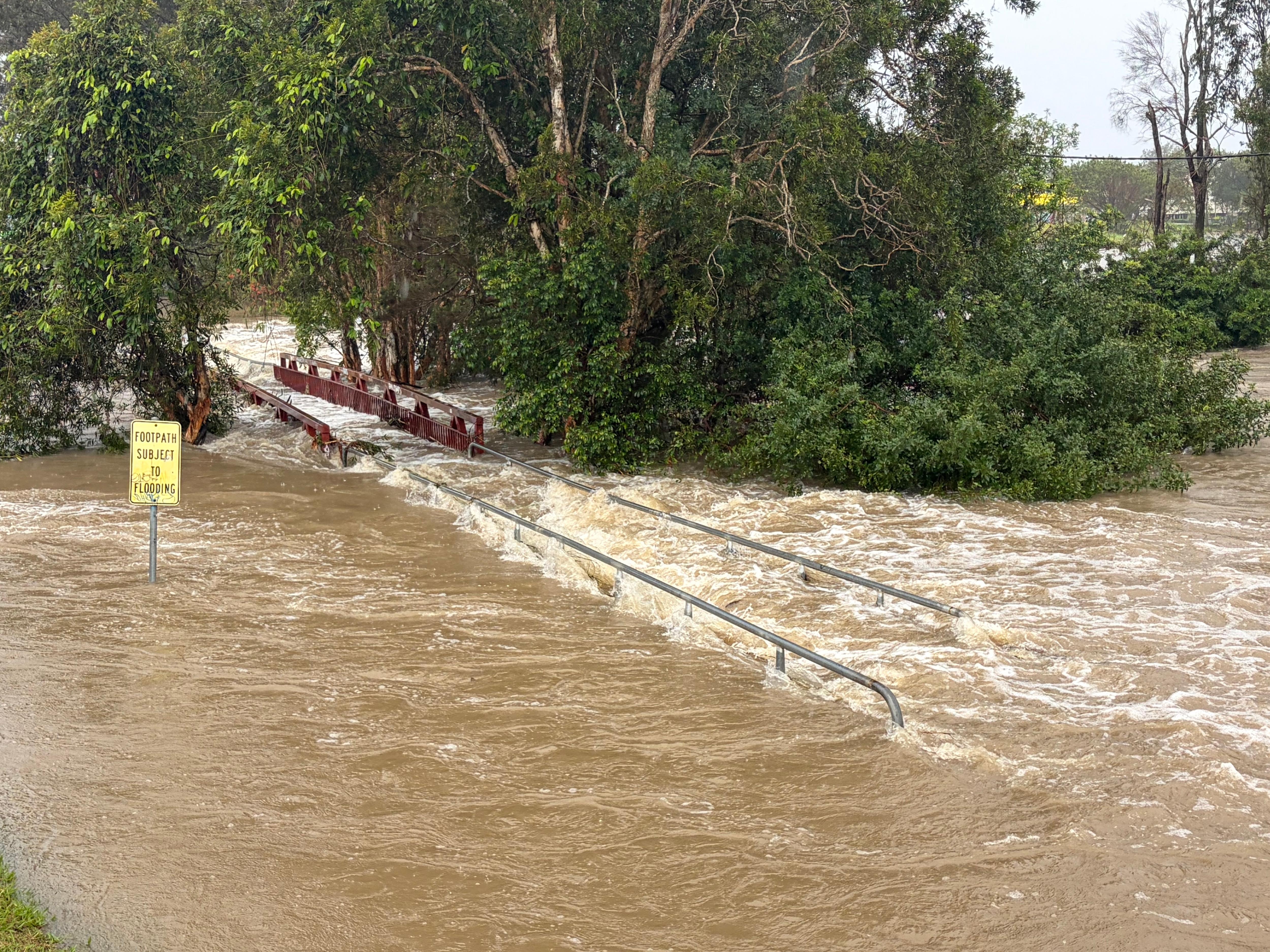 Fast-flowing floodwater over a bridge.