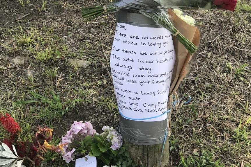 Flowers taped to a pole near a park