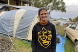 Woman wearing a black hoodie standing in front of a tent.
