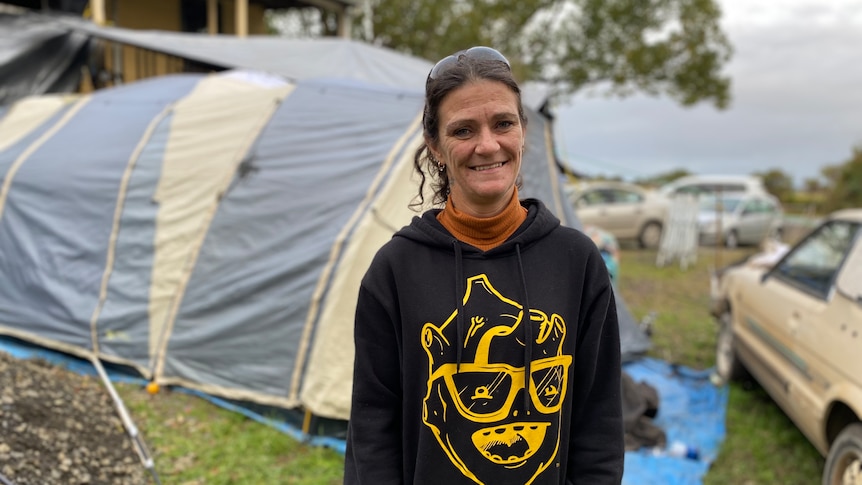Woman wearing a black hoodie standing in front of a tent.